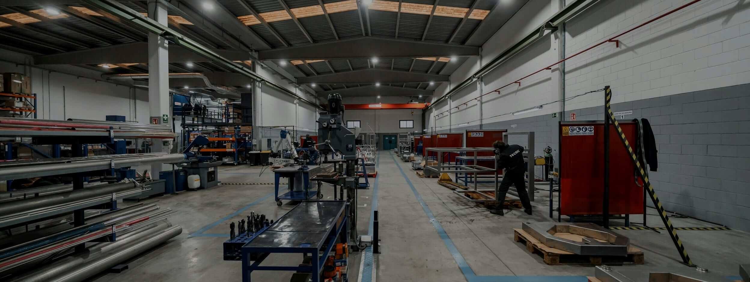 Atelier de tôlerie : racks de barres, perceuse, cabines de soudage et opérateur reliés à ISI®